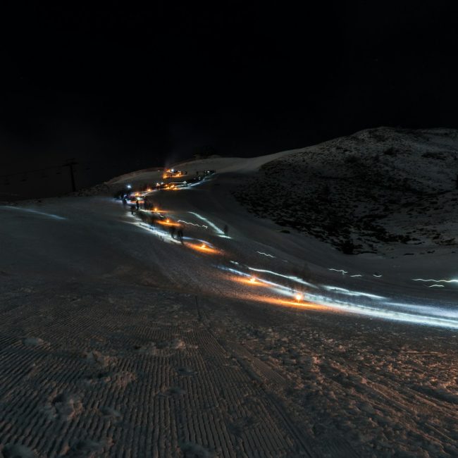 a long line of cars driving down a snow covered road