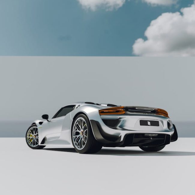 Rear view of a modern silver sports car against a bright blue sky with clouds.